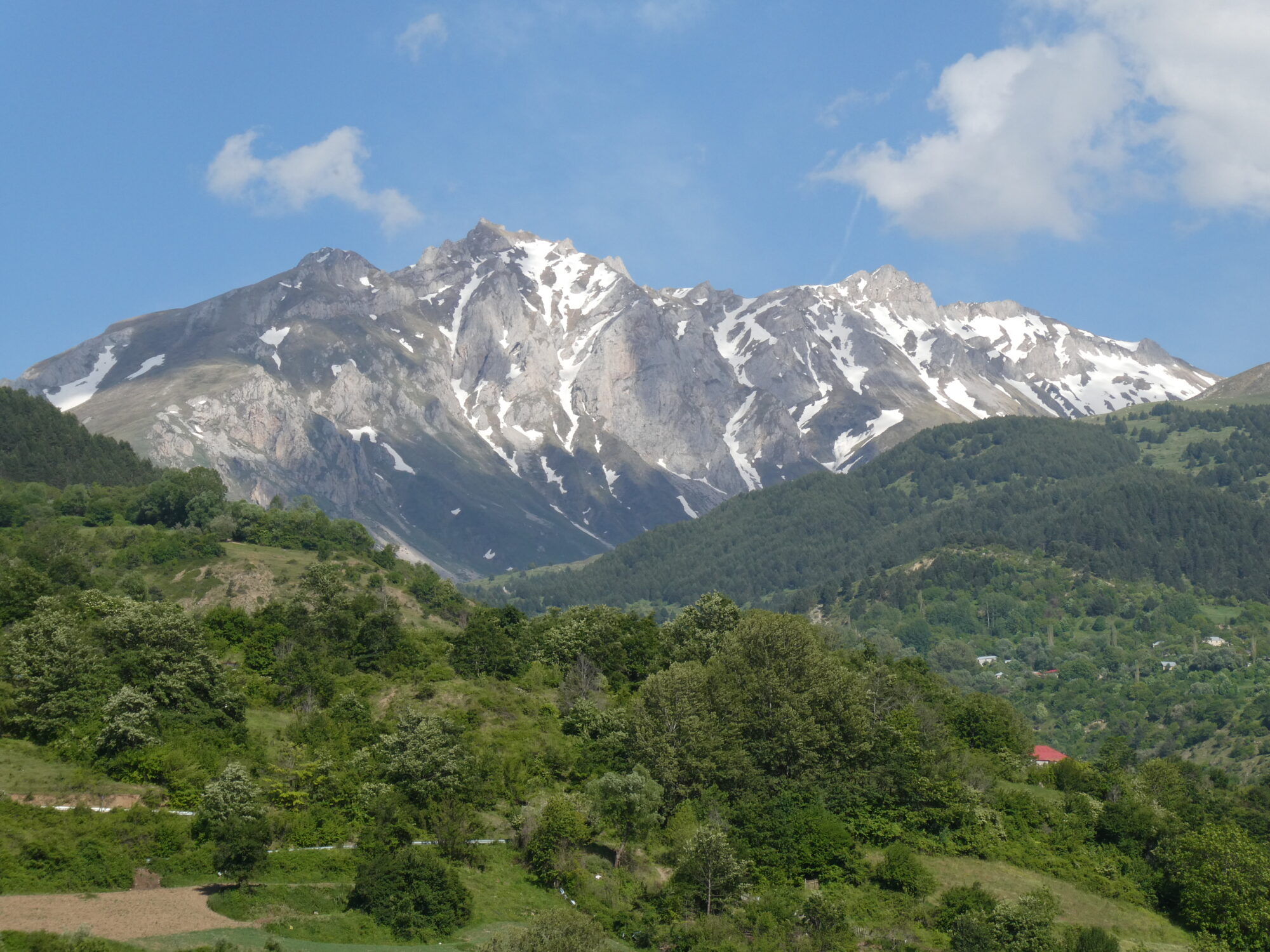 the snow-capped massif containing Mount Korab (2764 m above sea level) in June 2026 and viewed towards east. The bright grey rock cliffs consist of Devonian limestones. Photo credit: Kamil Ustaszewski.